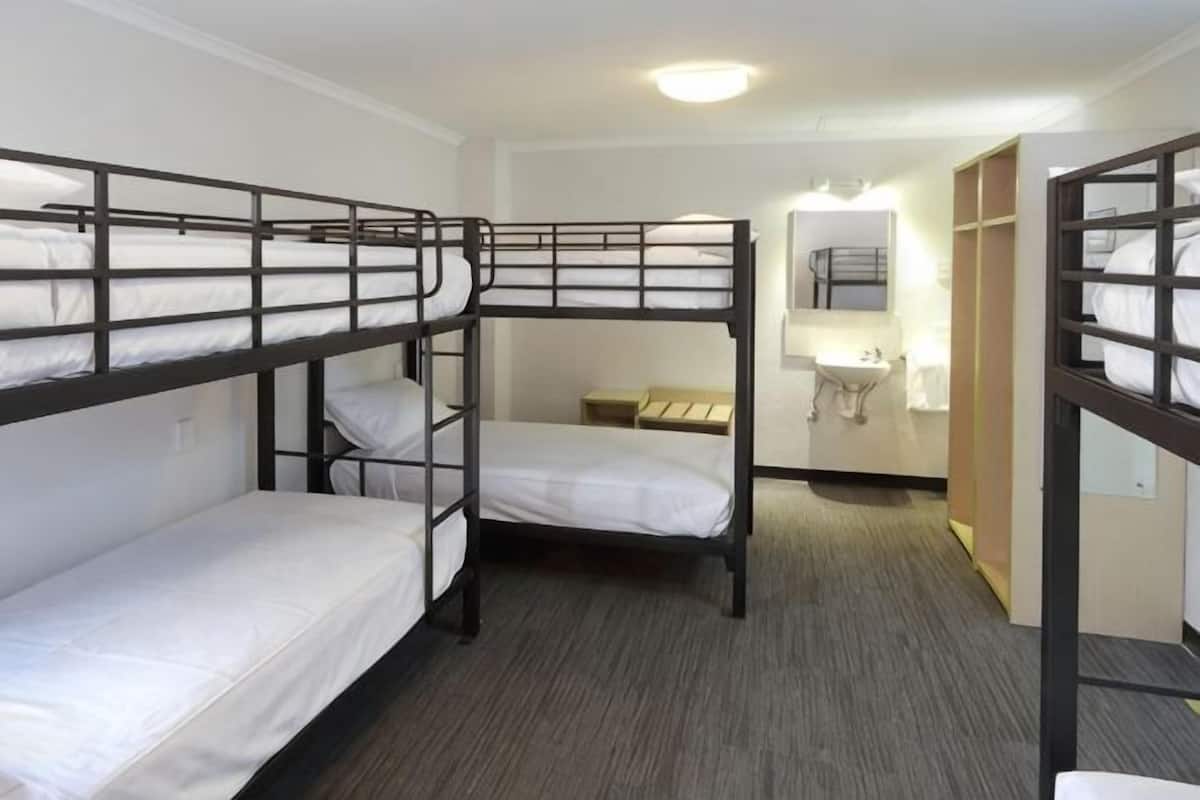 Dormitorio con literas, un lavabo y un espejo.