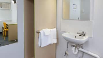 Un baño de hotel con lavamanos, espejo y toallero.
