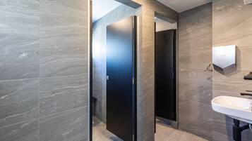 Un baño moderno con un espejo grande, un lavamanos y una puerta que da a otra habitación.