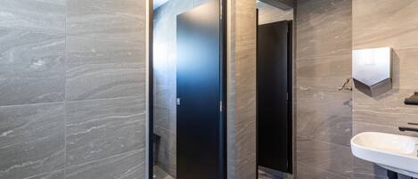 A modern bathroom with a large mirror, a sink, and a door leading to another room.