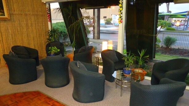 Un hall d’entrée avec plusieurs fauteuils de couleur sombre disposés autour d’un espace central agrémenté d’une petite table et de plantes en pot.