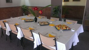 Un espace repas avec des tables dressées pour le repas, agrémenté d’un plateau de fruits et de sandwichs.