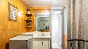 A compact bathroom with wooden walls, a sink, and a mirror. - Slouch Hat Hotel (Manila)
