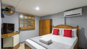 A hotel room with a bed, a TV, a wardrobe, and an air conditioning unit. - Slouch Hat Hotel (Manila)