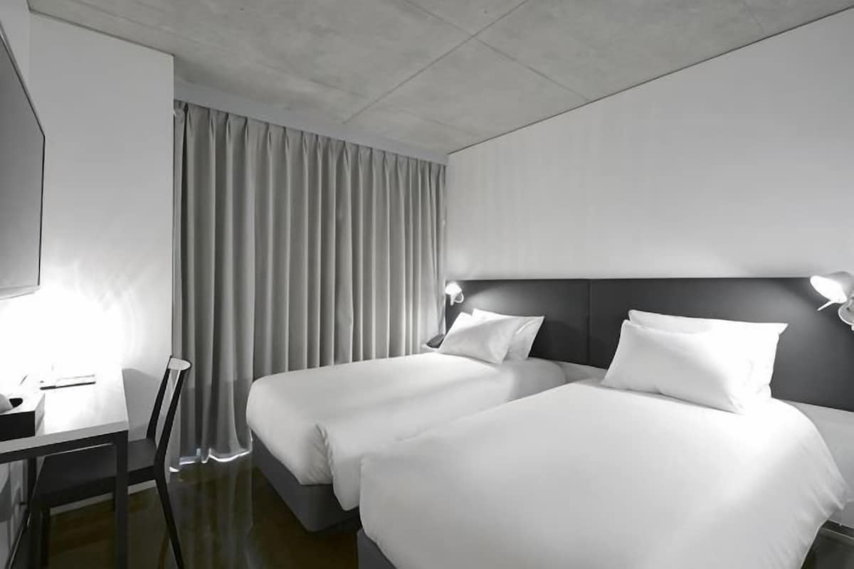Une chambre d’hôtel avec deux lits, un bureau et une chaise.