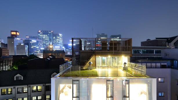 Un edificio moderno con varios pisos y una terraza en la azotea.