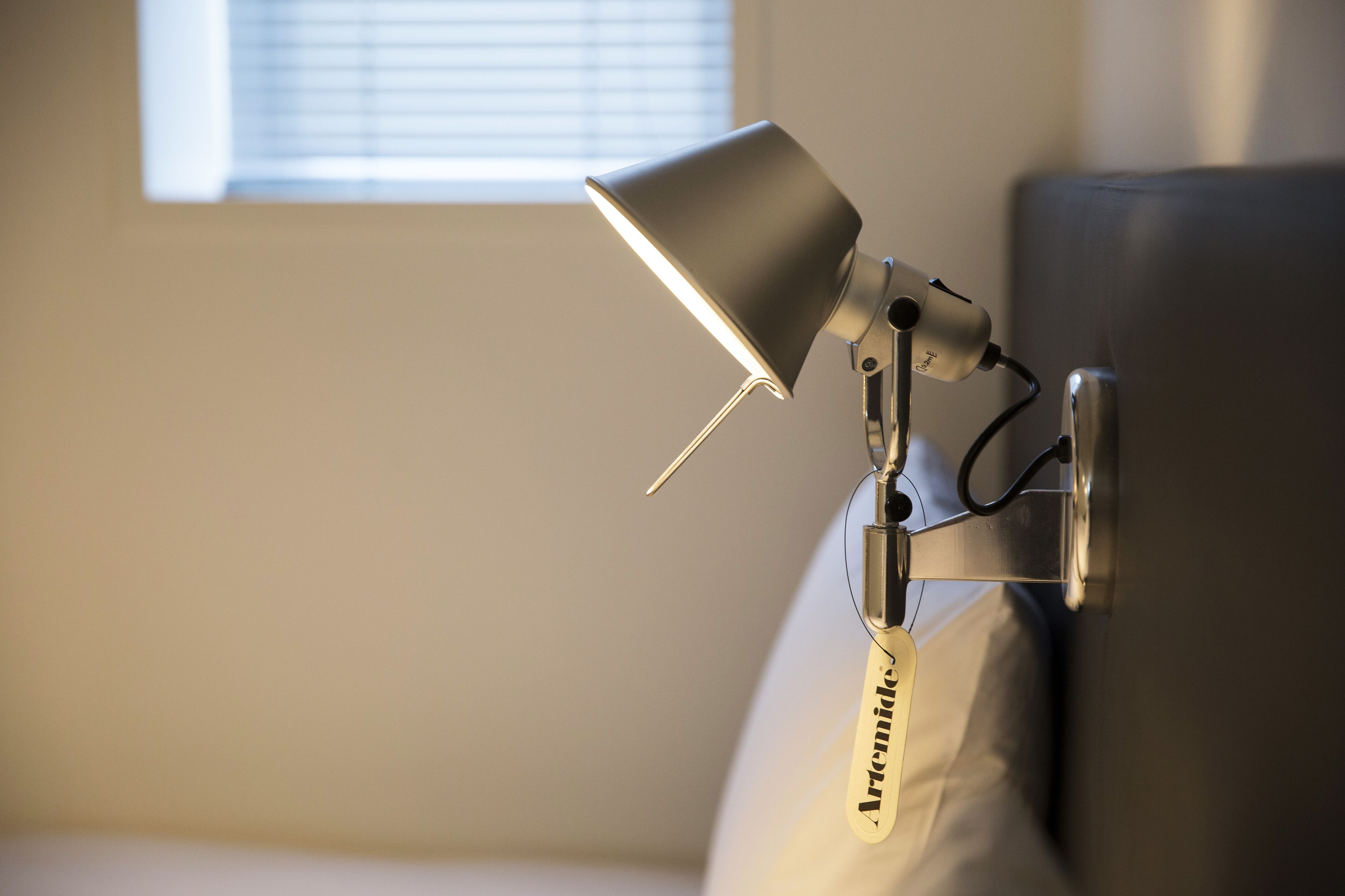 A wall-mounted desk lamp with a flexible arm, attached to a wall with a metal bracket.