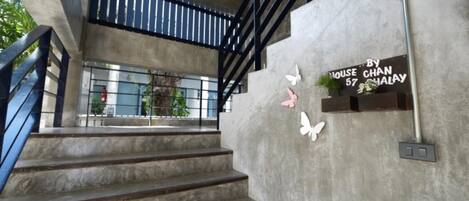 A staircase with a concrete wall and a sign that reads "HOUSE CHAN 57 HALALAY".