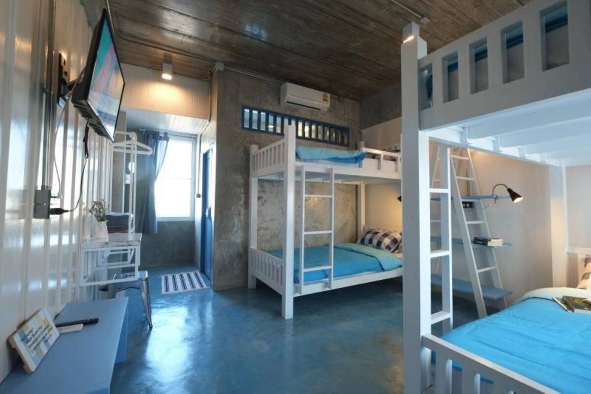 A bunk bed room with a desk and chair, a ladder, and a window.