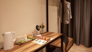 A wooden table with a white kettle, mugs, a small mirror, a vase with flowers, and a menu. - Lilai Travel - Lilia Motel (Taoyuan City)