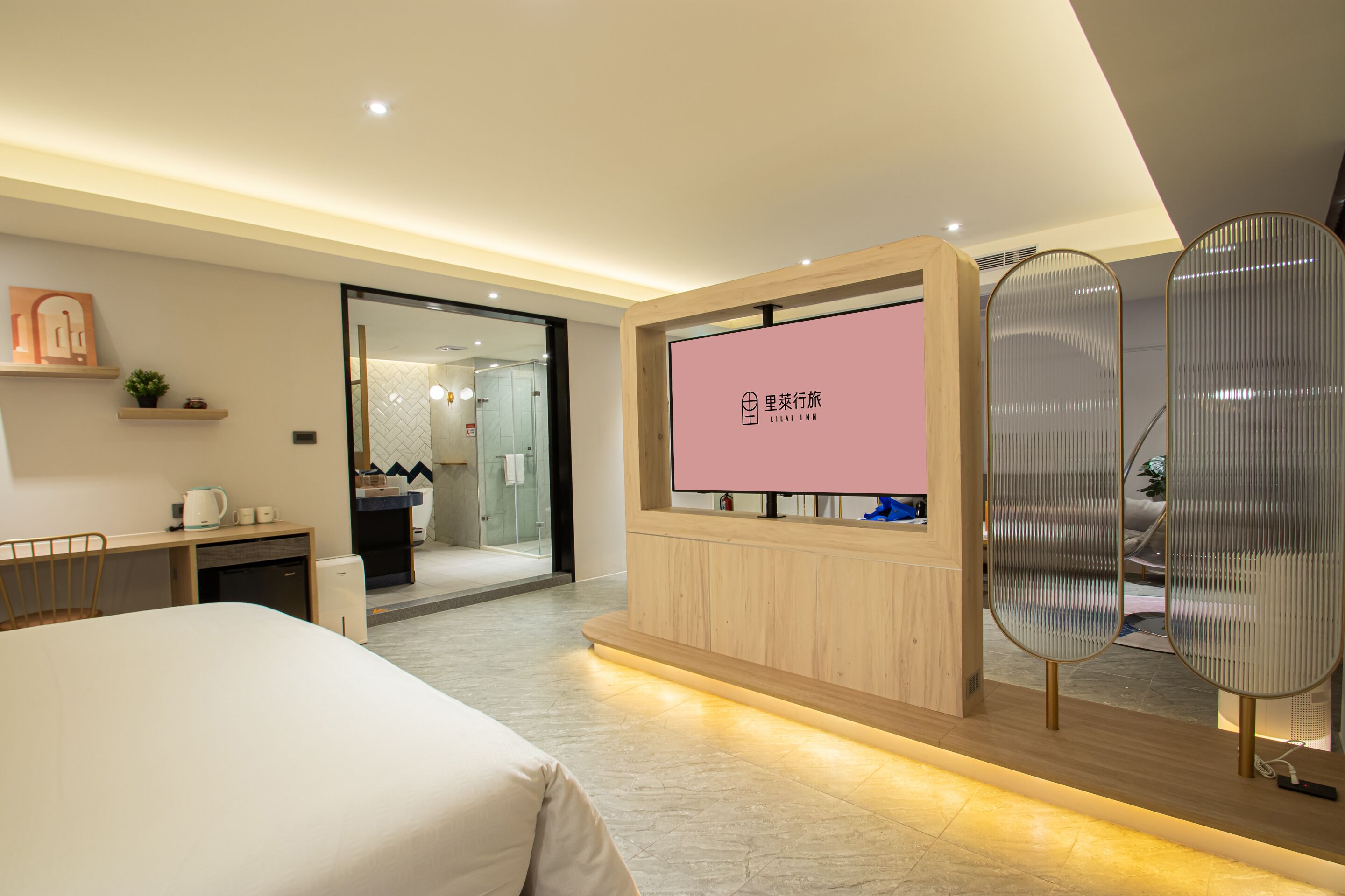 Habitación de hotel moderna con cama, escritorio y una pantalla de televisión que muestra texto.