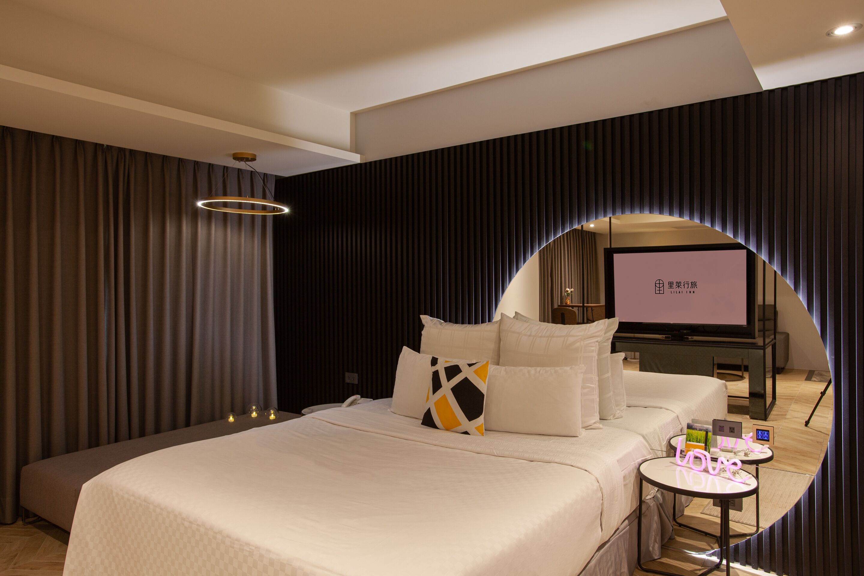 Una habitación de hotel moderna con una cama grande, una mesita de noche pequeña y una pantalla de televisión.
