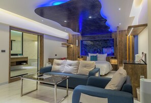 Een moderne hotelkamer met een groot bed, een bank, een glazen salontafel en een grote spiegel.
