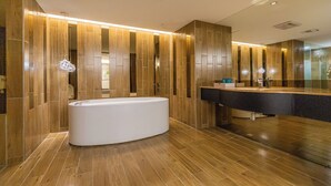 A modern bathroom with a large bathtub, wooden paneling, and a vanity with a mirror. - Lilai Travel - Lilia Motel (Taoyuan City)