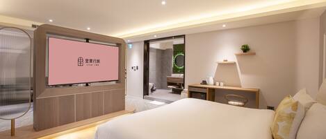 A modern hotel room with a large bed, a television, a desk, and a bathroom visible through an open door.