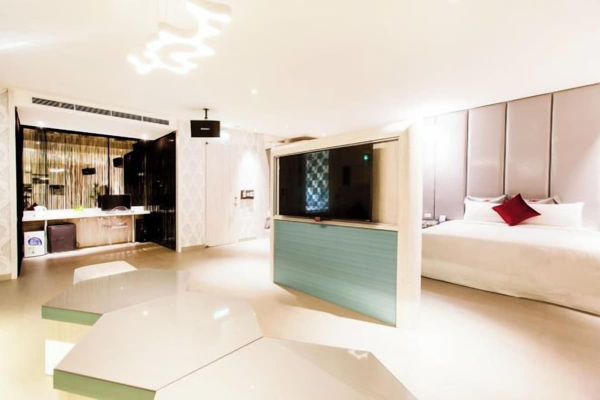 Una habitación de hotel moderna con cama, televisión, escritorio y zona de estar.