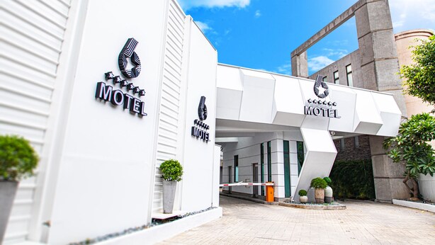 Un motel moderno con una entrada geométrica llamativa y varias plantas en macetas.