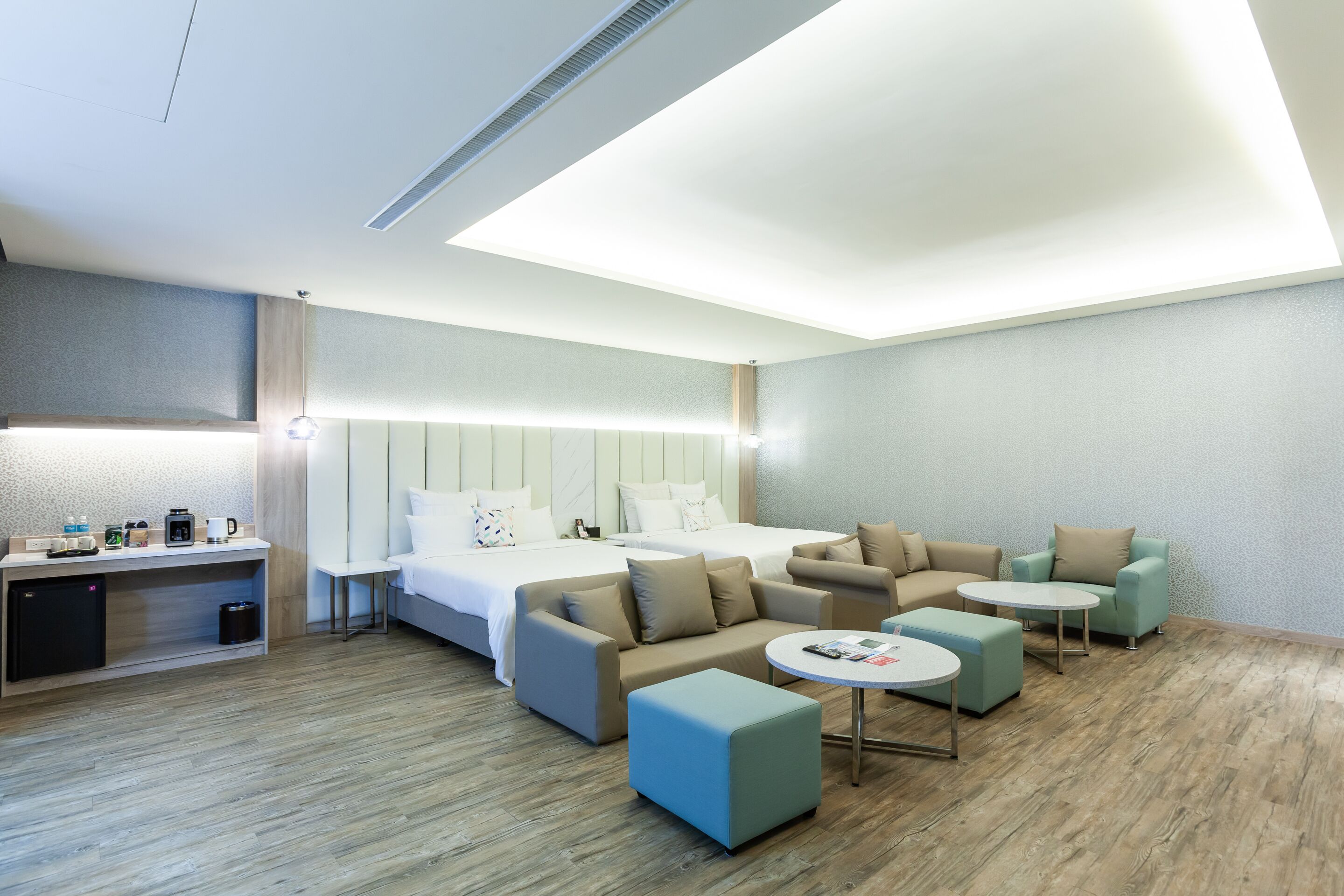 Een moderne hotelkamer met een bed, een bank, een poef en een kleine tafel.