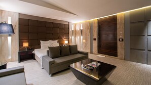 Una habitación de hotel moderna con una cama grande, un sofá, una mesa de centro y una mesita de noche.