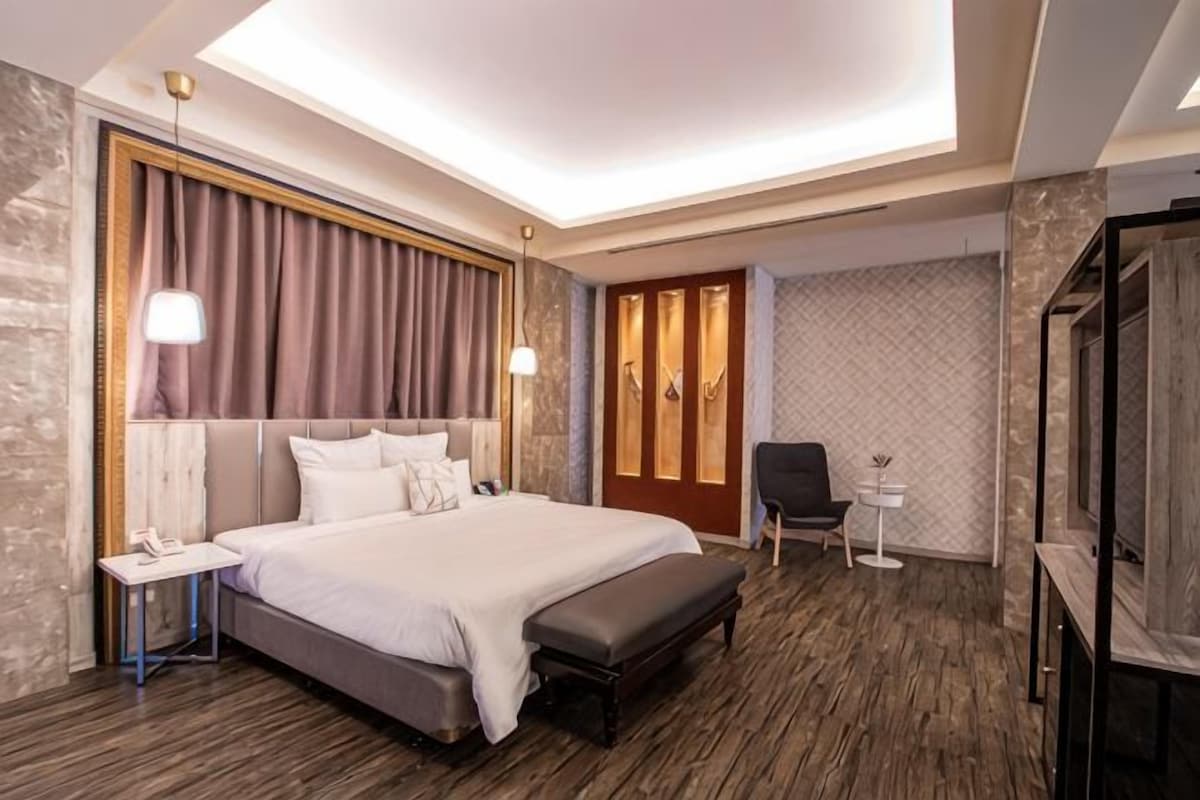 Una habitación de hotel moderna con una cama grande, mesitas de noche, un escritorio y una silla.