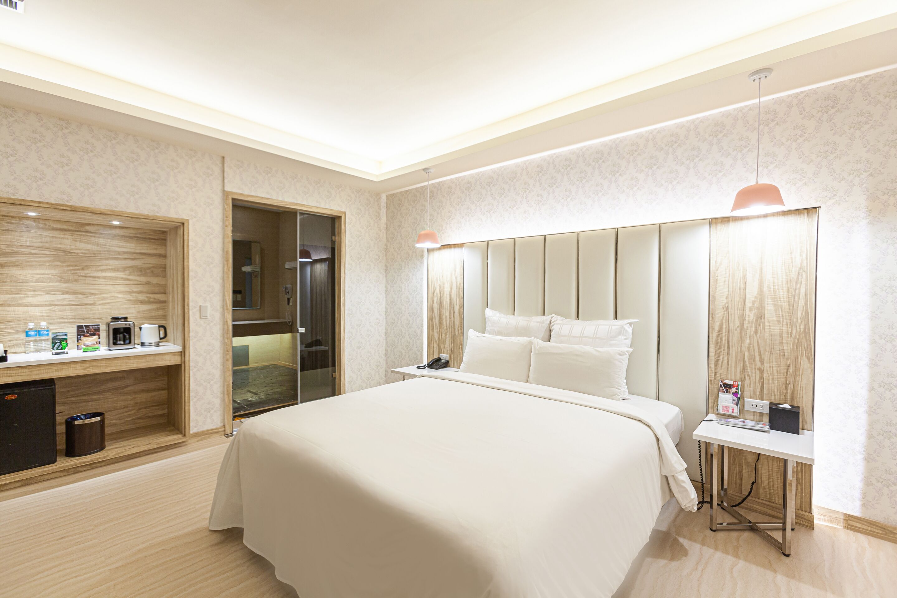 A hotel room with a large bed, bedside table, and a mirror.