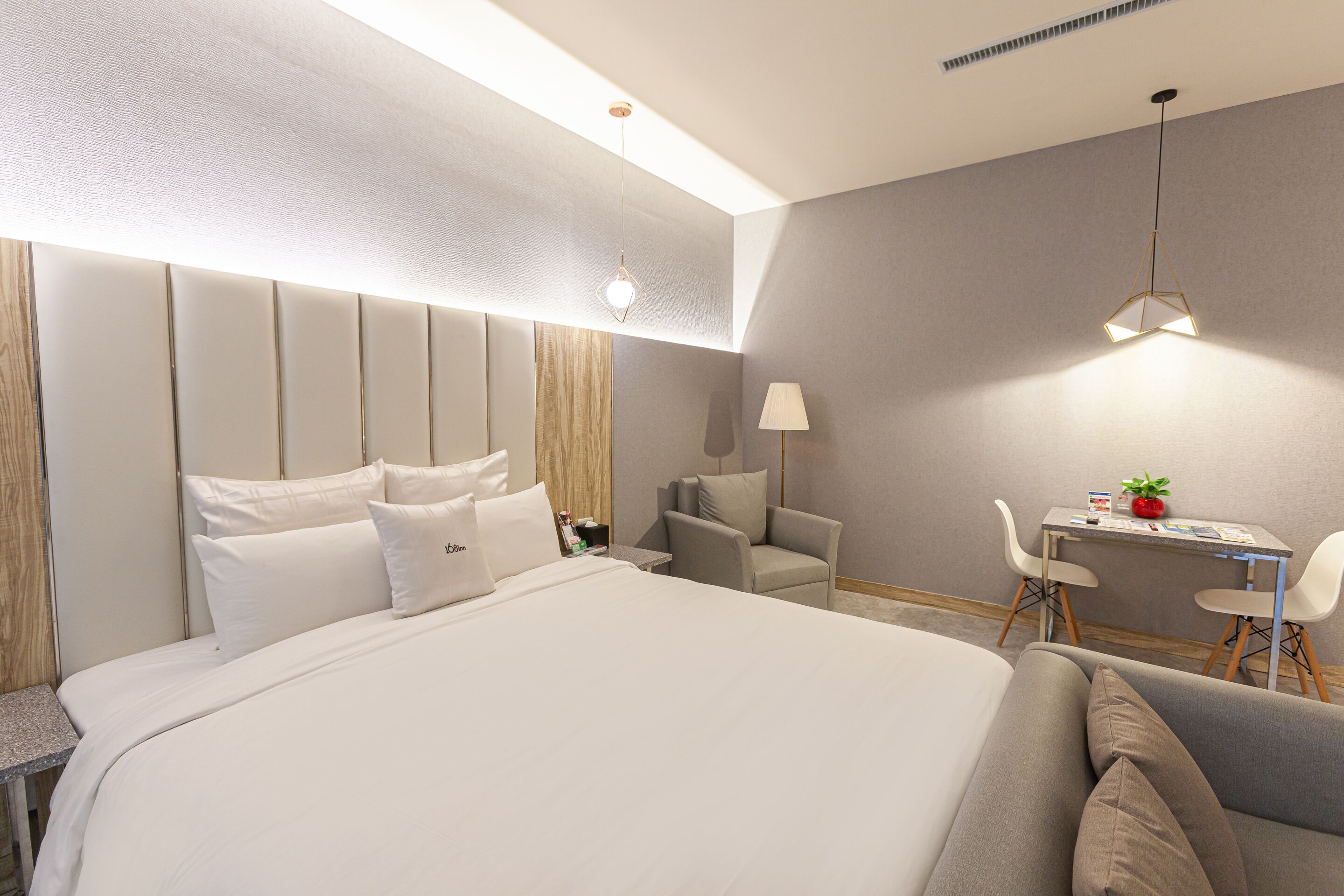 A modern hotel room with a large bed, a desk, and a chair.