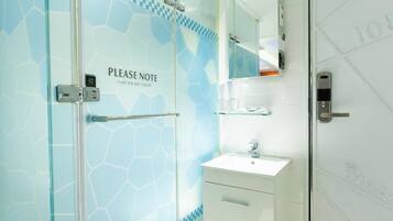 A bathroom with a glass shower door, a sink, and a mirror.