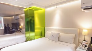 Une chambre d’hôtel avec deux lits, un mur d’accent vert, une tête de lit blanche, une lampe de chevet et un téléphone sur la table de chevet.