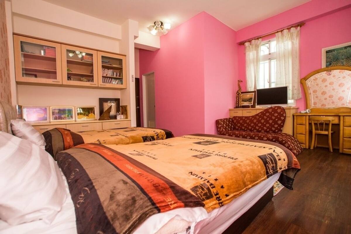 A bedroom with two beds, a desk with a computer, and a bookshelf.