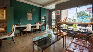 A cozy interior with a teal accent wall, a leather sofa, and a dining area with vintage chairs and a small TV. - Queen Love (Hualien City)