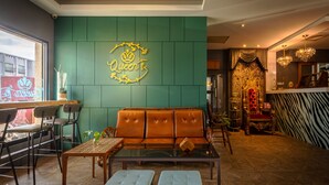 A cozy lounge area with a green wall, a neon sign reading "Queen's", and a plush orange sofa. - Queen Love (Hualien City)