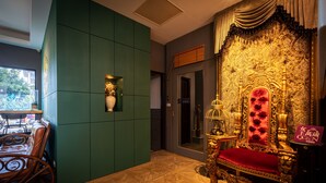 A luxurious room with a large ornate golden chair, a green wall, and a patterned wooden floor. - Queen Love (Hualien City)