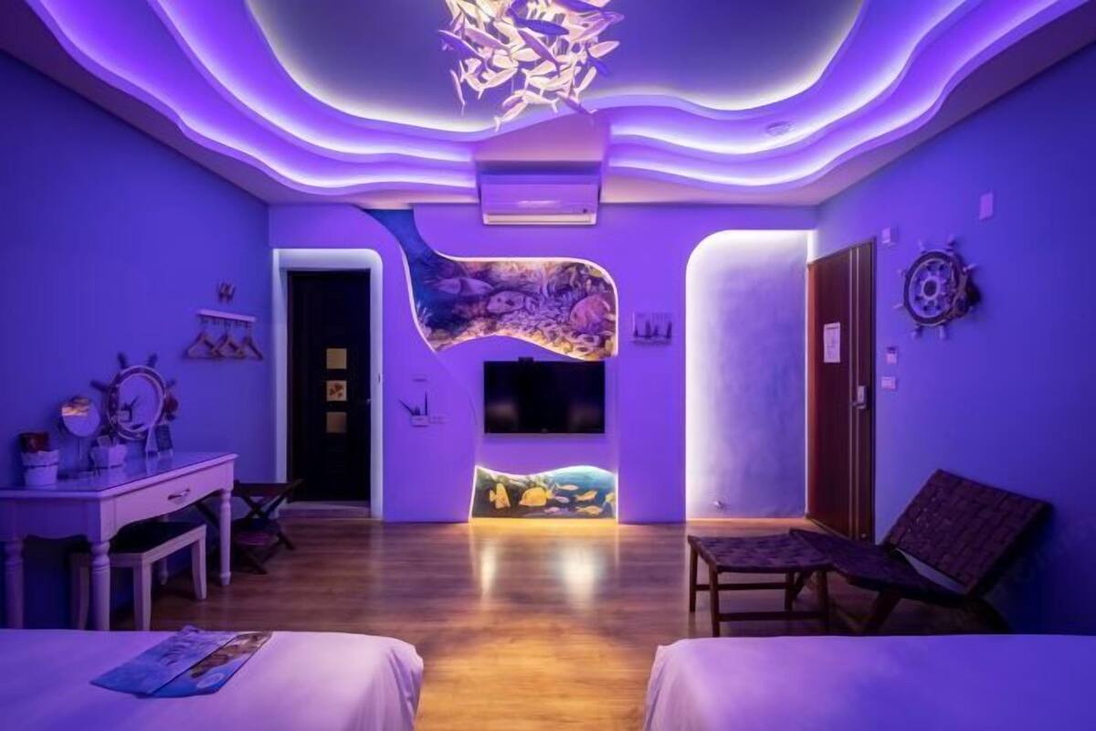 A modern room with a curved ceiling, a flat-screen TV, a bed, a desk, and a chair.