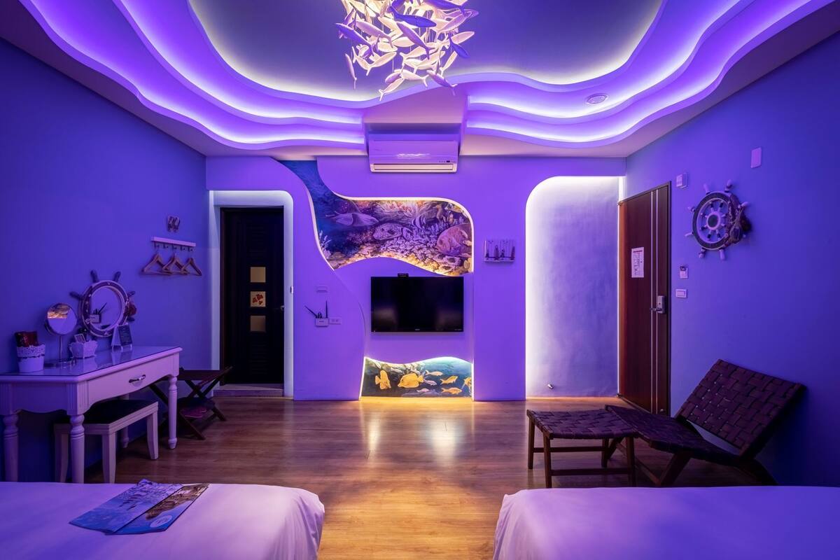 A room with a curved wall, a flat-screen TV, a desk with a mirror, and a bed.