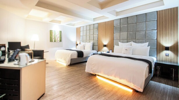 Camera d'albergo con due letti, una scrivania e un design moderno.