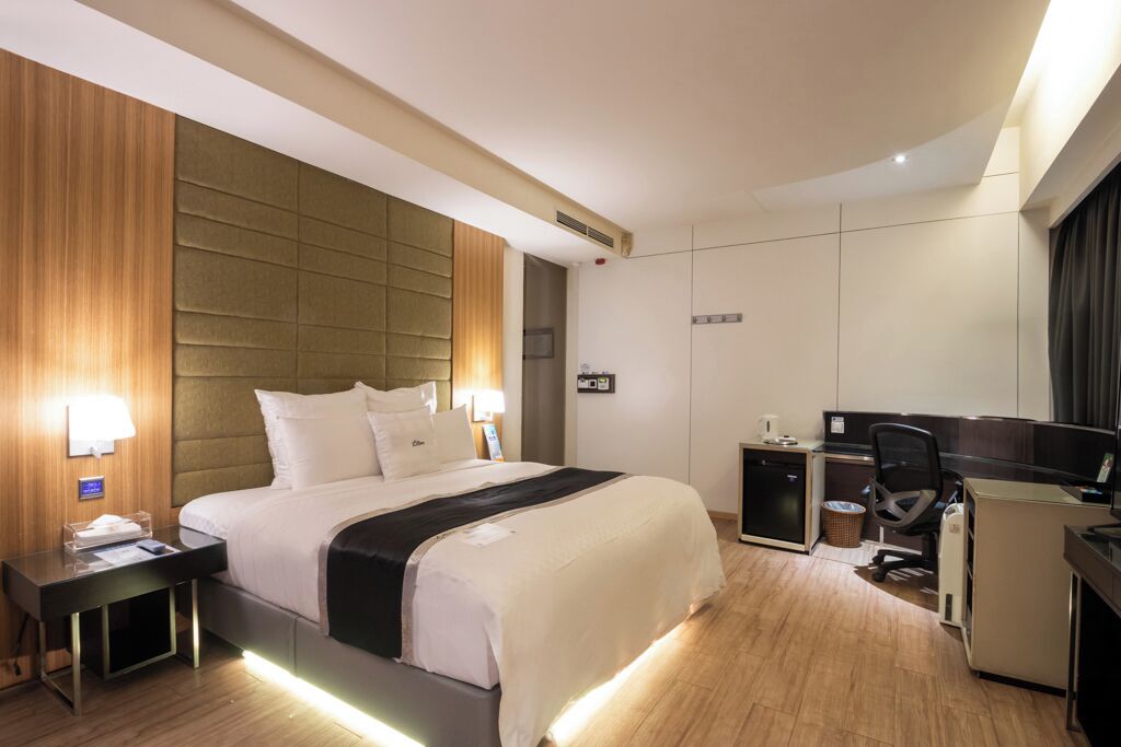 A hotel room with a large bed, bedside tables, a desk, and a chair.