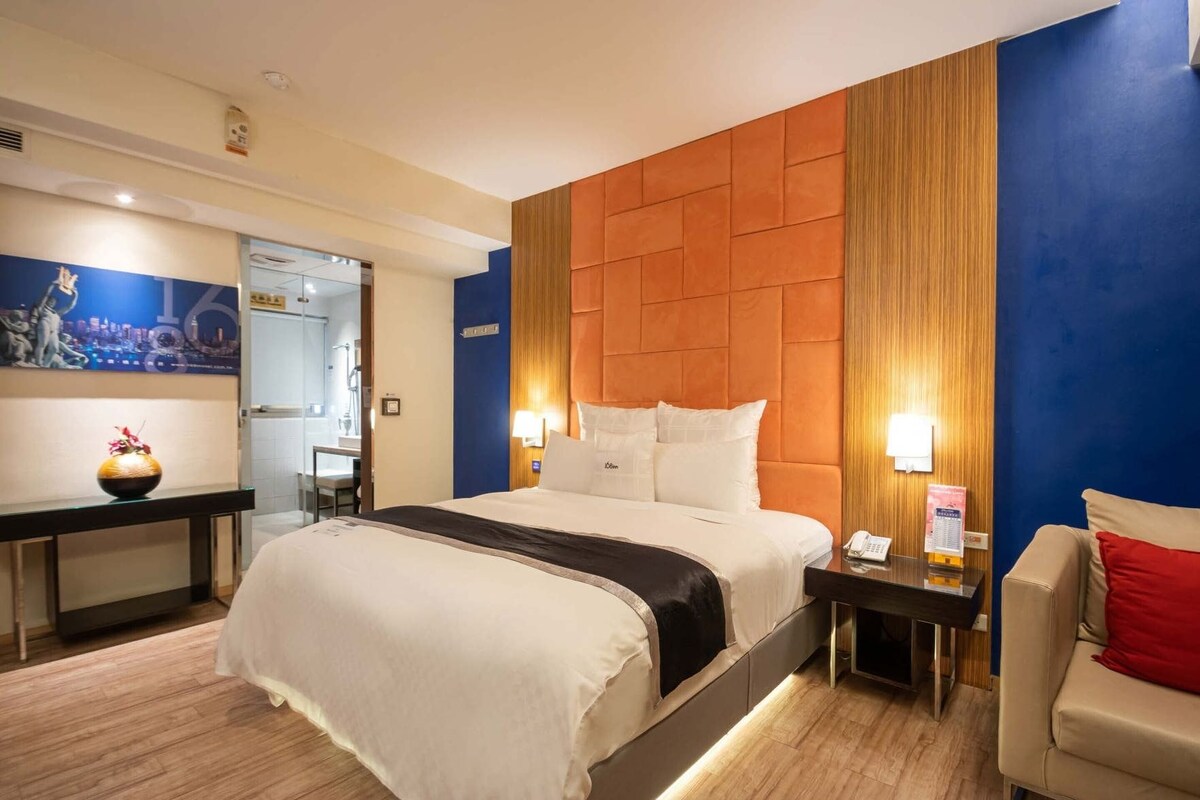 Une chambre d’hôtel comprenant un lit, des tables de chevet, une chaise, un bureau et un vase.