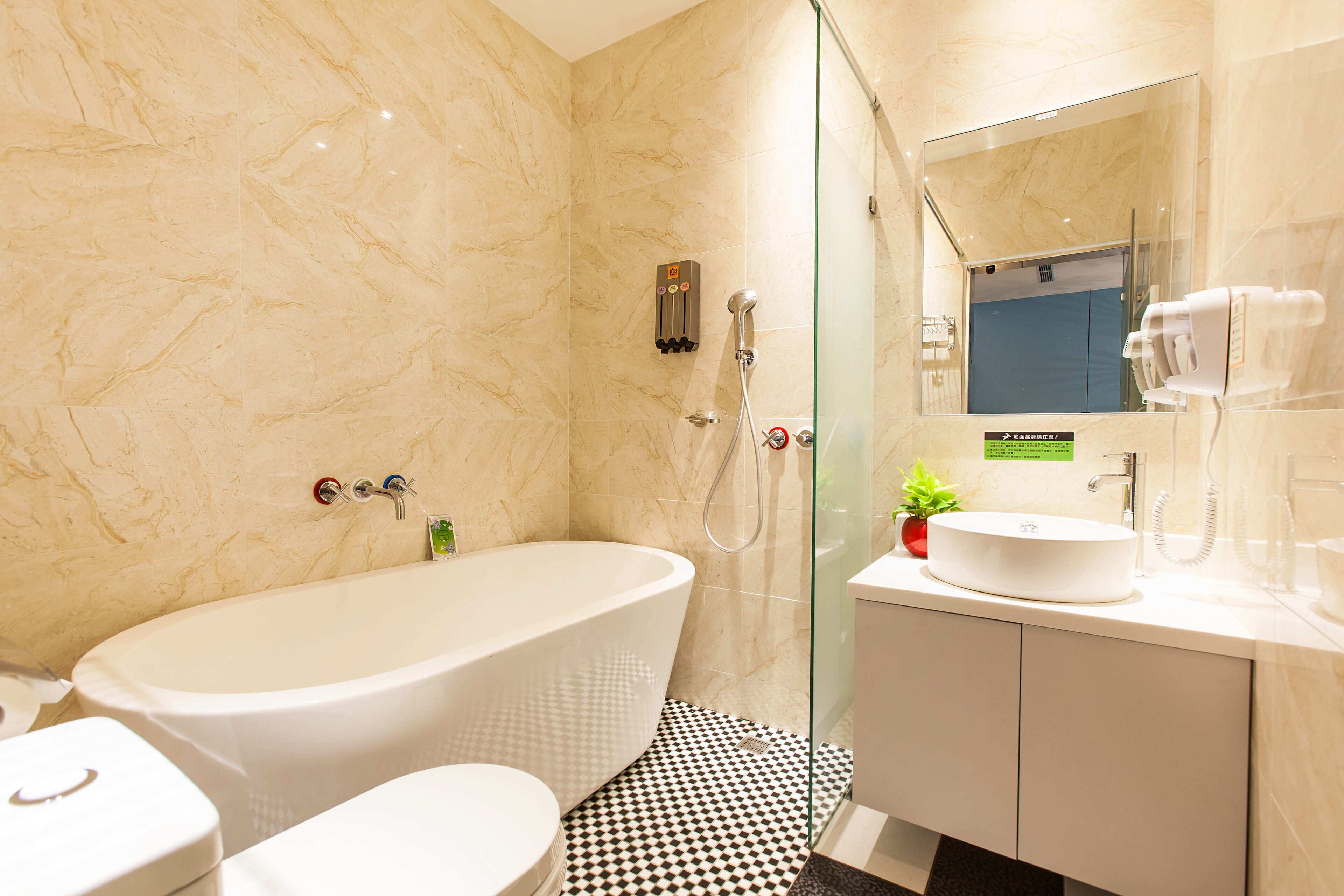 A modern bathroom with a freestanding bathtub, a glass-enclosed shower, a sink with a mirror, and a toilet.