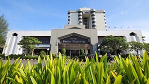 A hotel with a modern facade, a prominent entrance, and several flags on the roof. - The Putra Regency Hotel (Kangar)
