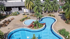 A swimming pool with a wavy design, surrounded by palm trees and benches. - The Putra Regency Hotel (Kangar)