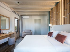 A hotel room with a large bed, a desk with a chair, a mirror, and a wall with wooden panels. - Elia Bettolo (Chania)