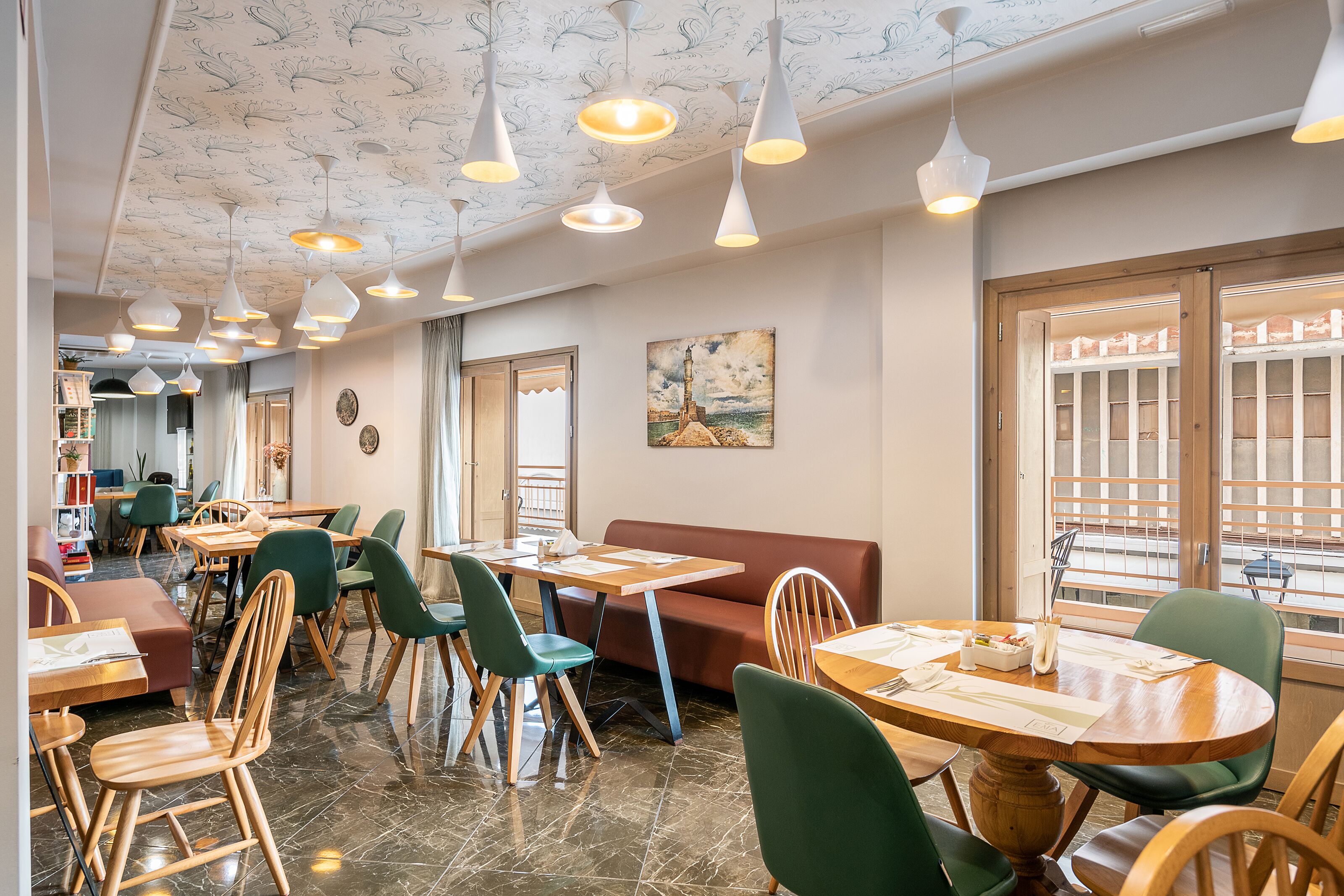 A restaurant with multiple tables and chairs, a sofa, and a painting on the wall.