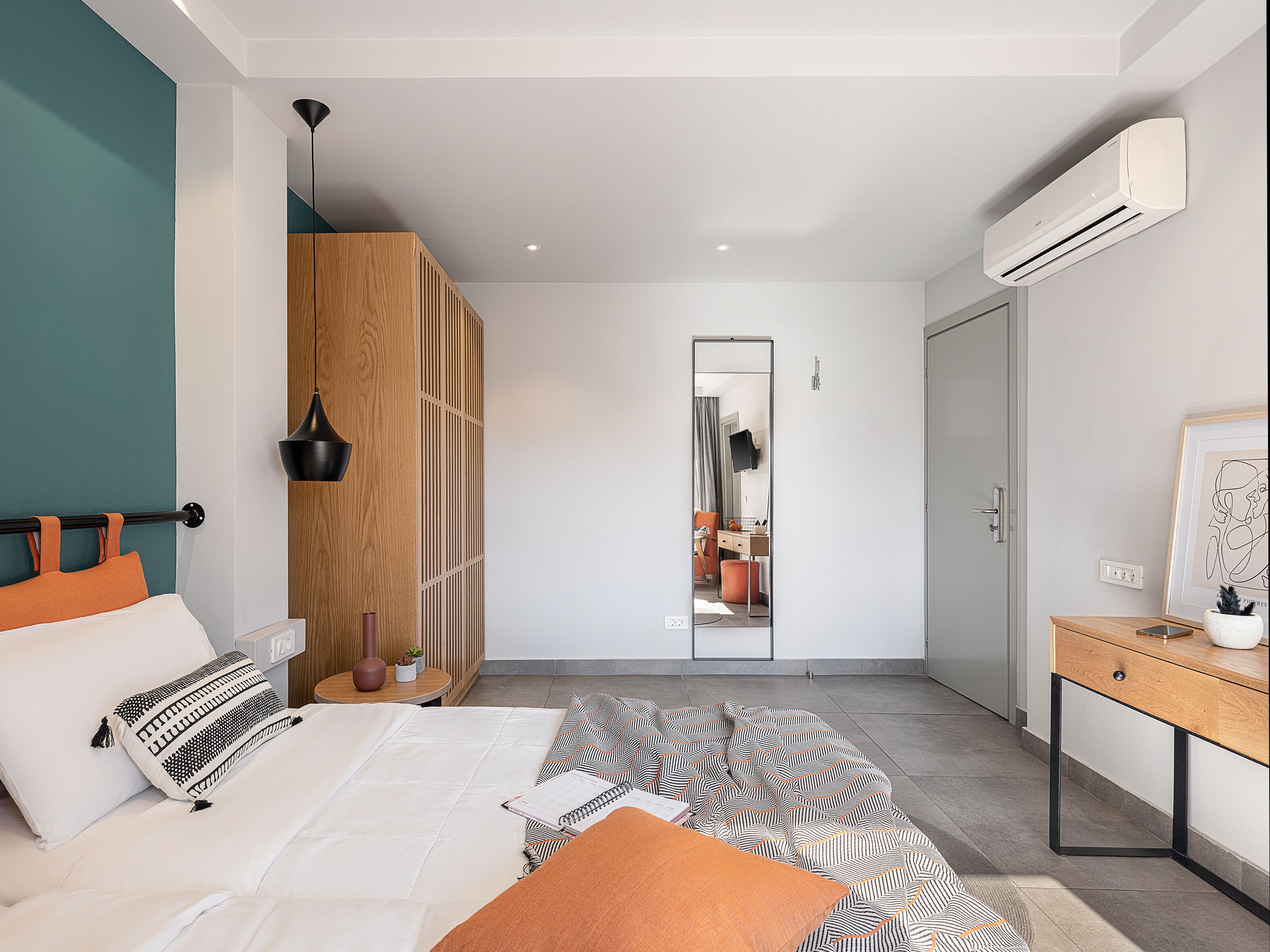 Een moderne slaapkamer met een bed, bureau en airconditioning.