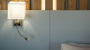 Ένα σύγχρονο μπάνιο με έναν τοίχο επενδυμένο με ξύλινα πάνελ, ένα φωτιστικό τοποθετημένο στον τοίχο και μια εμφανής βρύση.