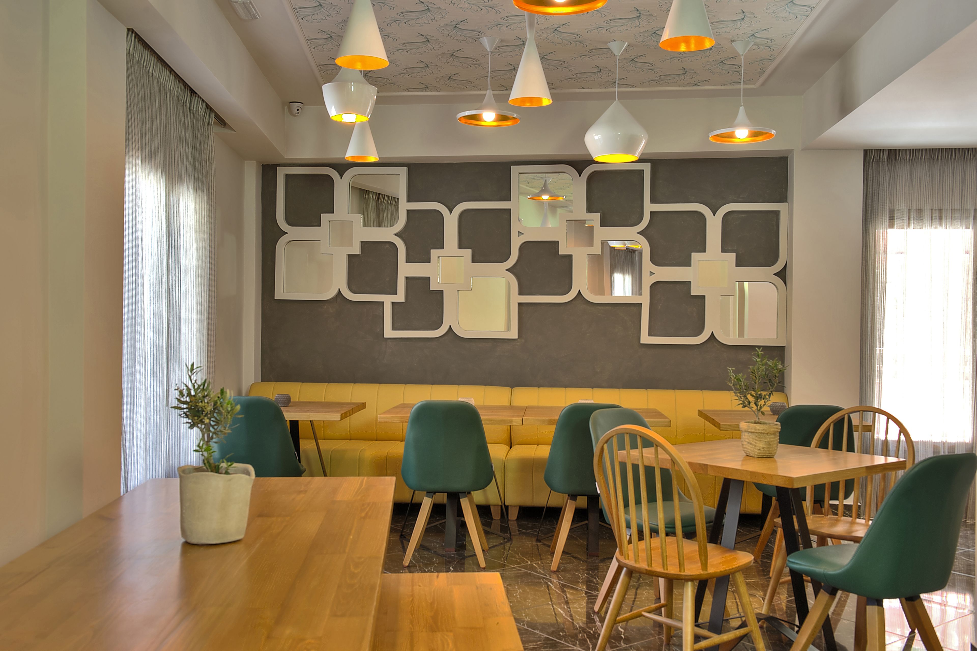 A modern dining area with a wooden table, green chairs, and a yellow sofa.