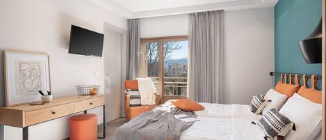 A modern bedroom with a bed, desk, and a view of the outdoors.