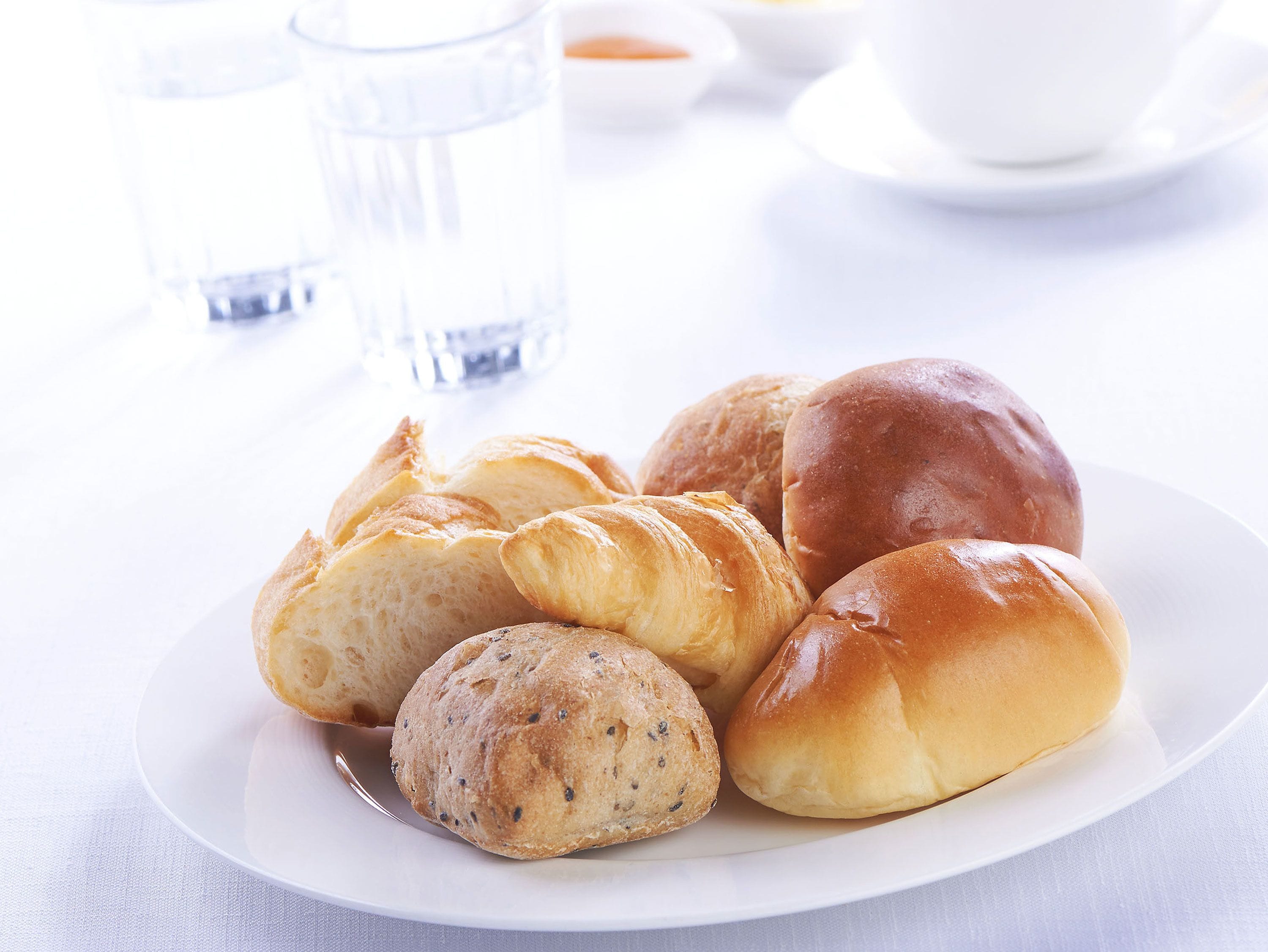 A plate of assorted bread rolls on a white tablecloth.