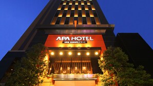 Um edifício alto com uma placa chamativa do APA HOTEL.