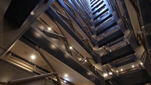 Um interior moderno com vários níveis, escadas e vigas estruturais.