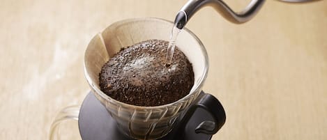 A coffee pot pouring water into a glass cup with a filter.